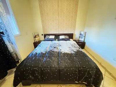 a bedroom with a bed with a black comforter at Jardin mohammedia in Mohammedia