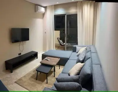 a living room with a blue couch and a tv at Appartement Oasis in Casablanca