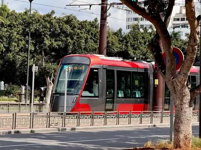 a red and gray train traveling down a street at Appartement Sacré-Cœur in Casablanca