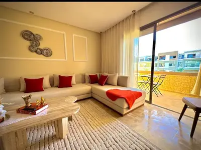 a living room with a white couch with red pillows at Kawtar in Mansouria