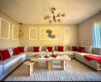 a living room with a large couch and red pillows at Kawtar in Mansouria