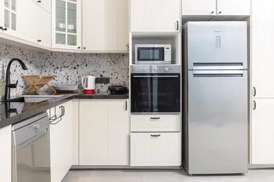 a kitchen with white cabinets and a refrigerator at Beach Vibe Villa - Sunny Stay in O Ben Slimane