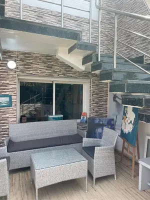 a patio with a couch and chairs and a brick wall at Chambres Surf,Piano et Arts in Tamaris