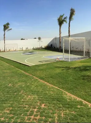a tennis court with palm trees and a net at Résidence fal green bouskoura in Bouskoura