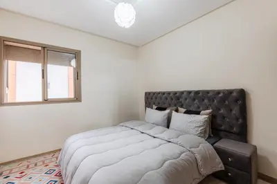 a bedroom with a large bed and two windows at Appartement au parc à 3 minutes de la plage in Mohammedia