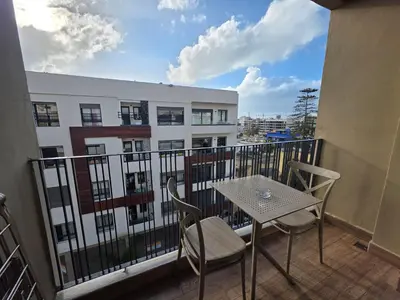 a balcony with a table and chairs and a building at Résidence EDEN 4 - Casablanca Center in Casablanca