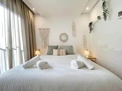 a white bedroom with a large bed with towels on it at Cozy Boho 2BR Prestigia Stadium View in Rabat