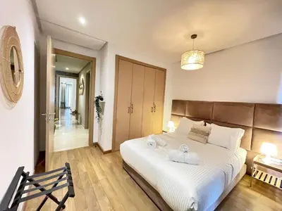 a bedroom with a large white bed with a wooden headboard at Cozy Boho 2BR Prestigia Stadium View in Rabat
