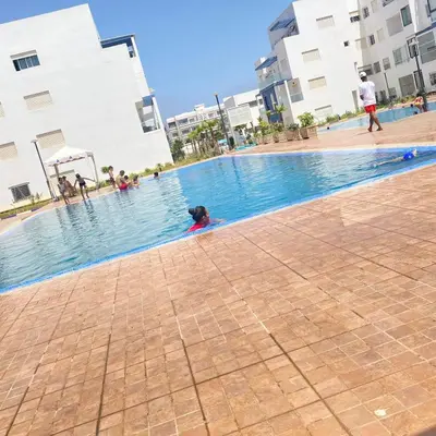 a dog swimming in a swimming pool in a building at Appartement avec piscine in Mohammedia