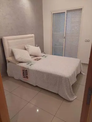 a bed with two pillows on it in a room at Appartement avec piscine in Mohammedia
