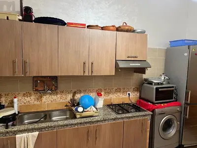 a kitchen with a sink and a stove and a microwave at Steps to the beach in Sidi Rahal