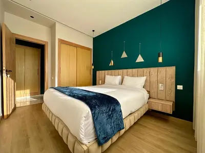 a bedroom with a large bed with a blue wall at CosmoStay Airport Casablanca Appart in Nouaseur