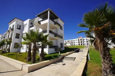 a white building with palm trees in front of it at Apartment Ocean View in O Ben Slimane