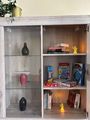 a wooden book shelf with glass shelves and books at Apartment with pool view, 1 min to beach, private parking in Mansouria
