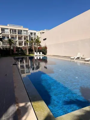 a swimming pool in front of a building at Cosy appart hotel Bouznika in O Ben Slimane