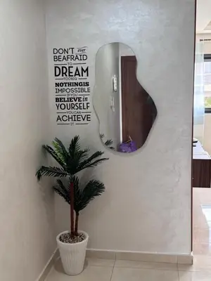 a mirror on a wall with a plant in a room at Cosy appart hotel Bouznika in O Ben Slimane