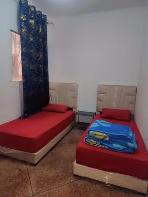 two beds in a room with red and blue sheets at Hachem in Rabat