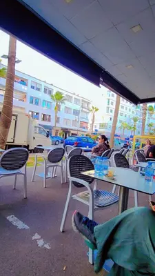 a group of tables and chairs with people sitting at them at Hachem in Rabat
