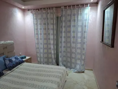 a bedroom with a bed and curtains in a room at Appartement vue panoramique in Bouznika