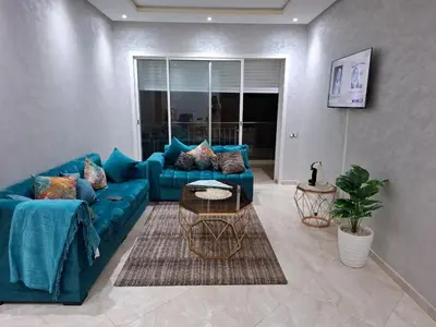 a living room with a blue couch and a table at Appartement vue panoramique in Bouznika
