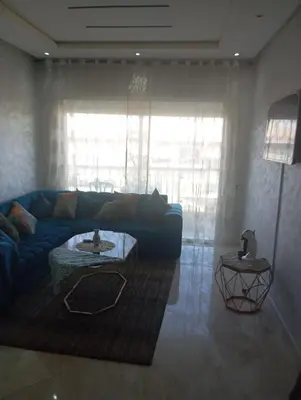 a living room with a blue couch and a table at Appartement vue panoramique in Bouznika