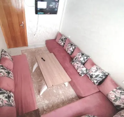 a red couch with pillows and a wooden table at Aeroport Tissir Appartement in Nouaceur