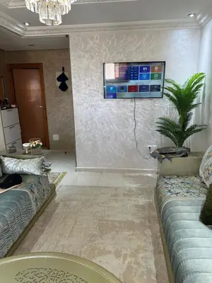 a living room with a couch and a tv on the wall at Ahmed 205 in Temara