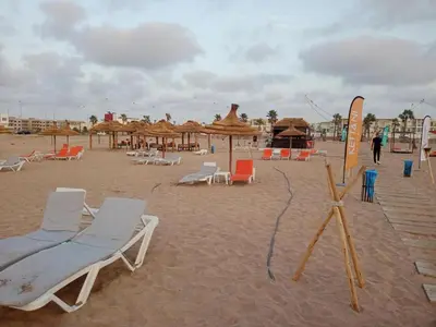 a beach with chairs and umbrellas on the sand at Casabay SidiRahal Appartement à louer in Sidi Rahal