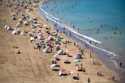 a crowd of people on a beach with umbrellas at Housse moderne Versailles in Rabat
