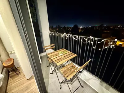 a table and chairs on a balcony at night at Central Luxurious & Great Location Ultra Fast Wi-Fi In The Heart Of Casablanca Oasis Disrict With A City View in Casablanca