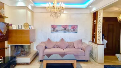 a living room with a pink couch and a chandelier at Bel appartement in Mohammedia