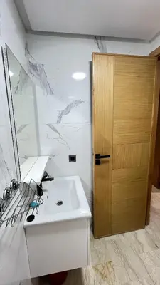 a bathroom with a sink and a wooden door at Zahira New Luxury Near The Beach - Entire Apartment in Casablanca