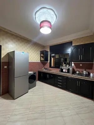 a large kitchen with black cabinets and a refrigerator at Longement moderne à Rabat in Rabat