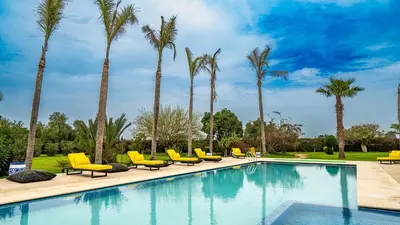 a swimming pool with yellow chairs and palm trees at Domaine Terra Cotta - Villa de luxe avec piscine sans vis-à-vis in Souk el Had