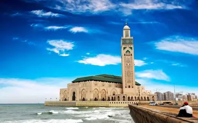 a large building with a clock tower next to the ocean at Ain Diab Sunrise Nest & Parking in Casablanca