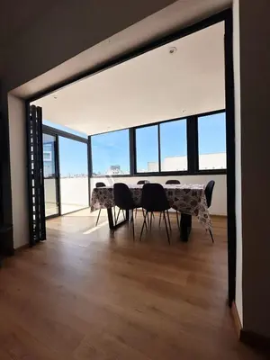 a dining room with a table and chairs in a room with windows at Stylish loft with view and terrace Maarif Gauthier in Casablanca