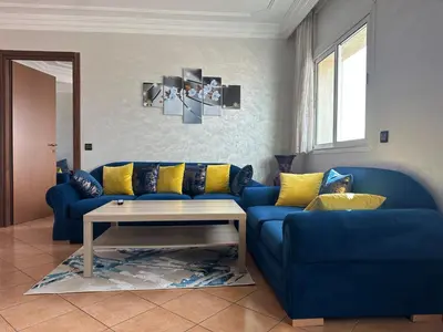 a living room with a blue couch and a table at Signorina appartamento in Temara