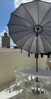 a table and chairs with an umbrella on a balcony at Wifaq temara in Temara