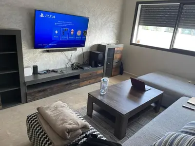 a living room with a couch and a tv at Appartement Ferme Bretonne en face de l'OCP - 2 Min CFC in Casablanca