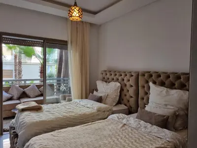 a bedroom with two beds and a large window at Appartement vue piscine à 3min de la plage bouznika in Bouznika