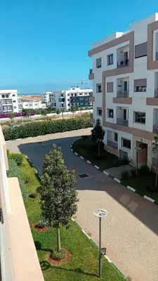 an apartment building with a tree in the middle of a street at Les jardins d'Atlantis Dar Bouazza in Tamaris
