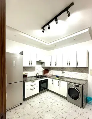 a kitchen with white cabinets and a washer and dryer at Apartment Majorelle Garden in Casablanca