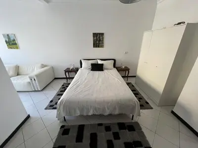 a white bedroom with a bed and a couch at Spacieux appartement proche de la mer in Casablanca