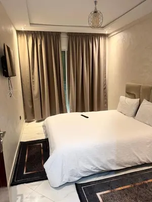 a bedroom with a large white bed and a window at résidence Amina in Rabat