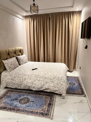 a bedroom with a bed with curtains and rugs at résidence Amina in Rabat