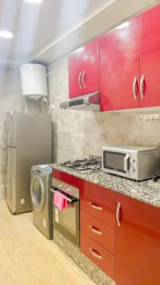 a kitchen with red cabinets and a stove and a microwave at Living Like Home in Casablanca