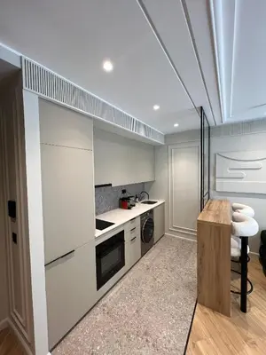 a kitchen with white cabinets and a wooden table at Appartement Le Claridge in Casablanca