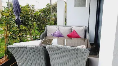 a porch with two wicker chairs and pillows at Ground floor apartment - Residence Skhirat Beach 2 in Skhirat