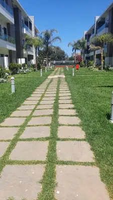 a walkway in the grass in front of a building at Ground floor apartment - Residence Skhirat Beach 2 in Skhirat