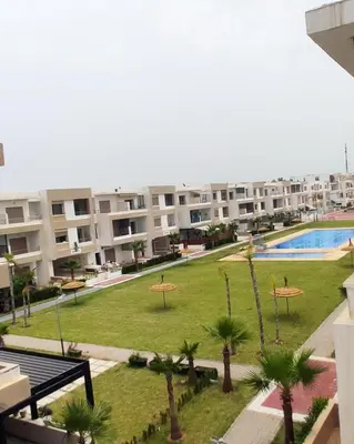 an apartment complex with a park with palm trees and a swimming pool at Belle Appartent Vue Piscine A Malaga Beach A Mansouria in Mansouria